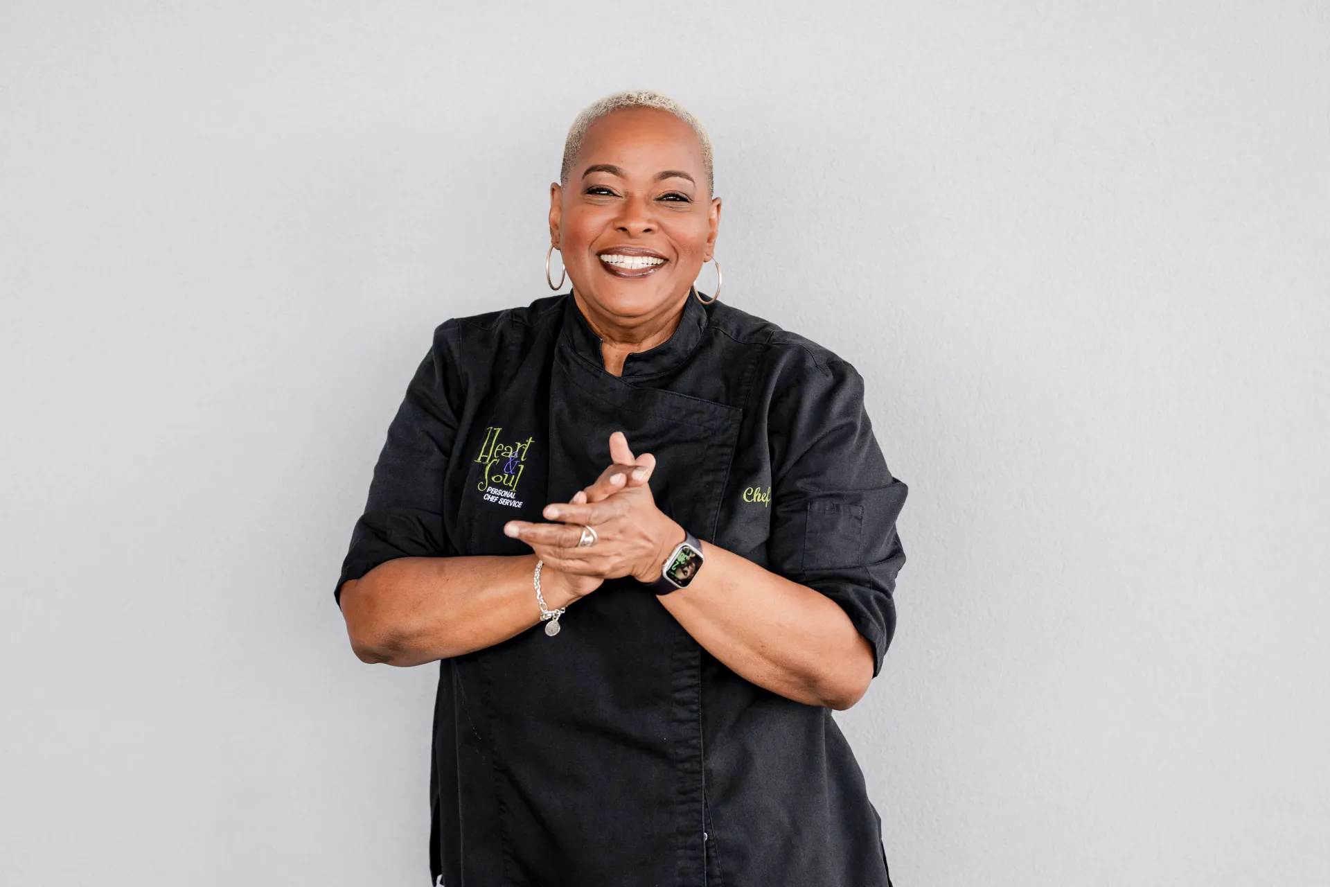 Chef Lisa Brooks in her black Heart and Soul chef coat, hands clasped with a warm smile
